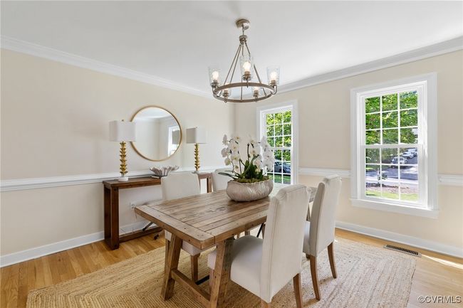 Dining room with a chandelier, light wood finished floors, crown molding, and chair rail. Double doors to kitchen and foyer. | Image 9