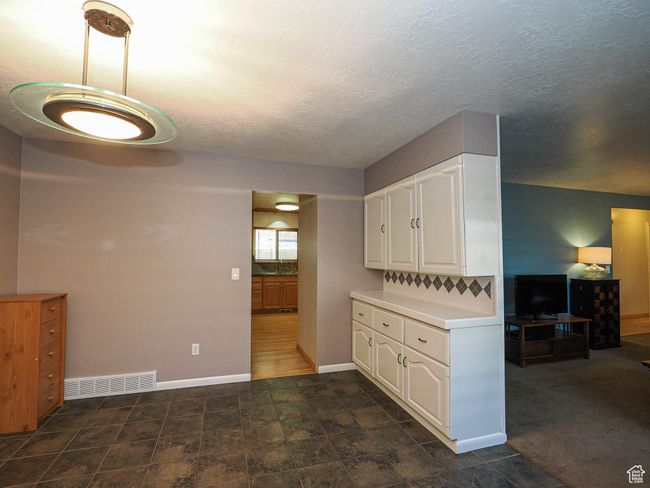 Kitchen featuring white cabinets, light countertops, baseboards, and a textured ceiling | Image 16