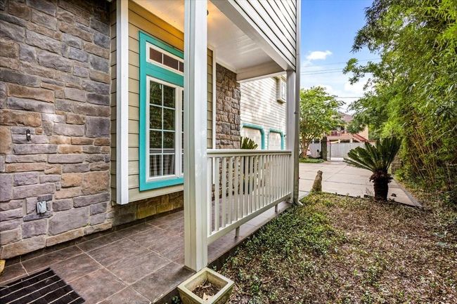 Charming bayfront entry welcomes you with classic exposed stone, lush landscaping, and the timeless elegance of an English Carriage House, complete with a covered porch, balcony, and vibrant gardens—perfect for relaxing in a serene coastal setting. | Image 6