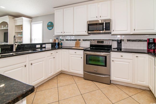 Kitchen with appliances with stainless steel finishes, a sink, tasteful backsplash, white cabinetry, and a textured ceiling | Image 27