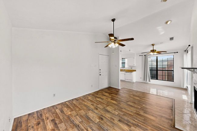 Unfurnished living room featuring wood finished floors, lofted ceiling, a ceiling fan, a fireplace, and baseboards | Image 18