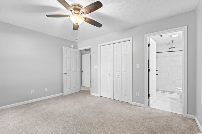 Unfurnished bedroom with carpet floors, a textured ceiling, a closet, ensuite bath, and a ceiling fan | Image 23