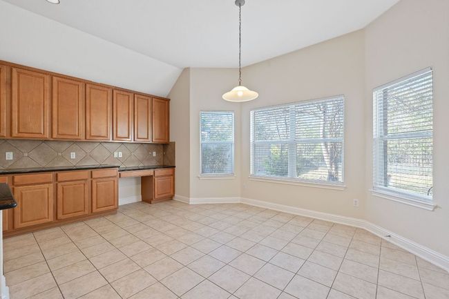 Kitchen featuring pendant lighting, lofted ceiling, dark countertops, built in desk, and decorative backsplash | Image 13