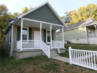 Bungalow-style home with a porch, a front lawn, and central AC unit | Image 2