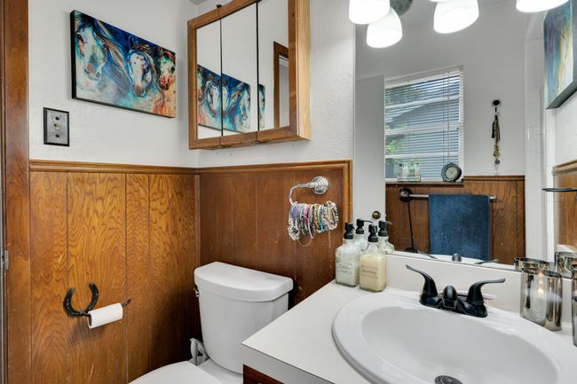 Half bath featuring toilet, a wainscoted wall, vanity, and wooden walls | Image 14