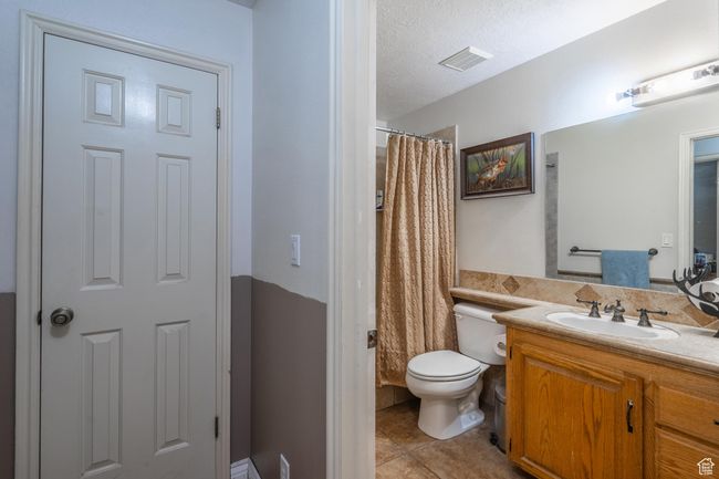 Full bathroom featuring tile patterned flooring, vanity, a shower with shower curtain, and a textured ceiling | Image 39