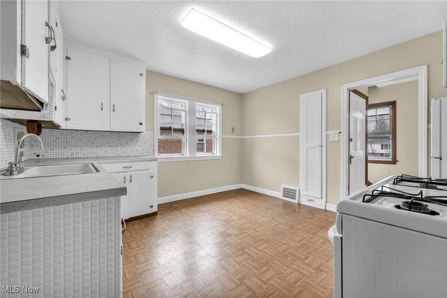 Kitchen featuring white gas range oven, a sink, visible vents, white cabinetry, and light countertops | Image 31