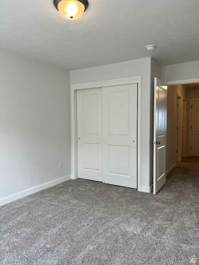 Unfurnished bedroom with carpet floors, a closet, and baseboards | Image 11