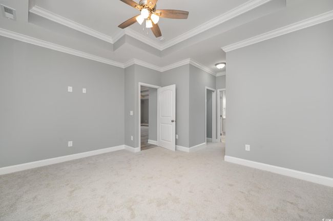 Spare room featuring a raised ceiling, light colored carpet, and crown molding | Image 16