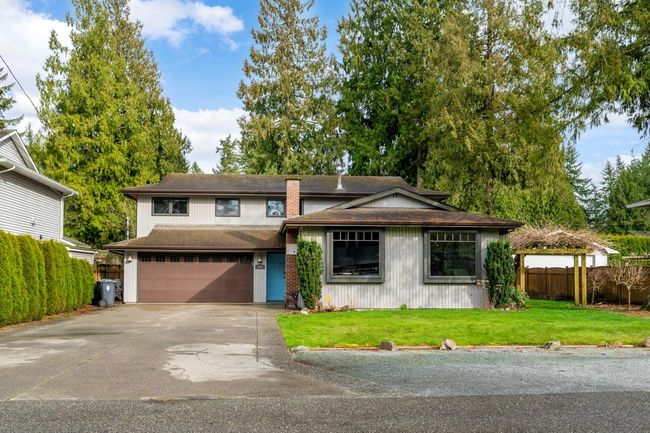 View of front facade featuring a shingled roof, a front lawn, fence, concrete driveway, and a garage | Image 26