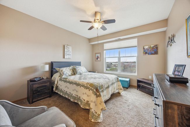Spacious primary ensuite bedroom featuring a large walk-in closet and private bath. A soft shade on the double-wide window provide natural light, and a ceiling fan adds to the comfort of this retreat. | Image 14