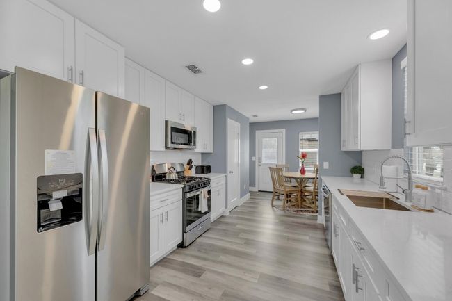 Kitchen featuring light countertops, stainless steel appliances, a sink, light wood finished floors, and visible vents | Image 13