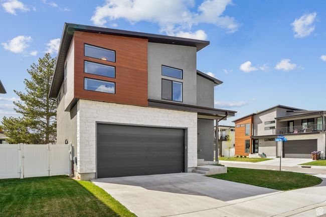 Contemporary house featuring a gate, fence, concrete driveway, stone siding, and a garage | Image 32