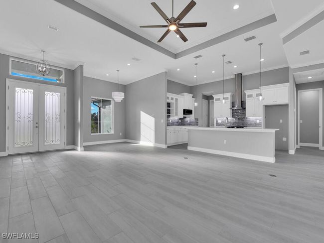 Unfurnished living room with ornamental molding, recessed lighting, light wood finished floors, a chandelier, and a ceiling fan | Image 8