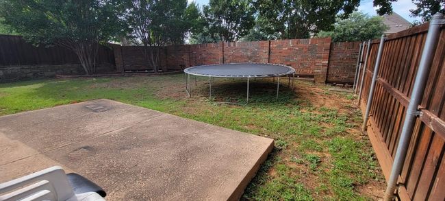 Fenced backyard with a trampoline and a patio | Image 15