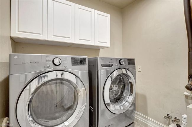 Washroom featuring washer and clothes dryer, cabinet space, and baseboards | Image 25