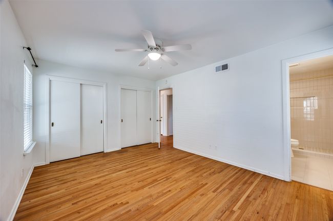Unfurnished bedroom featuring two closets, light wood-type flooring, ensuite bath, and ceiling fan | Image 9