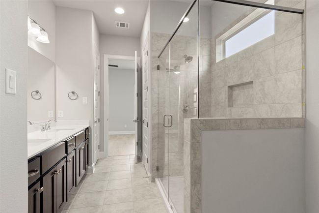 Bathroom with double vanity, a shower stall, and tile patterned flooring | Image 29