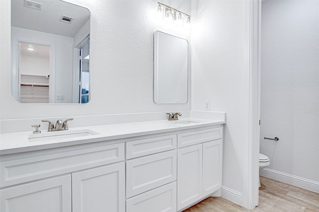 Full bathroom featuring wood finished floors, toilet, baseboards, and double vanity | Image 25