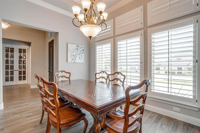 Dining space with crown molding, a chandelier, french doors, and light wood-style flooring | Image 10