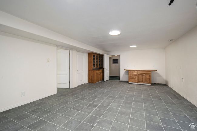 Finished below grade area with dark tile patterned flooring, bar area, and baseboards | Image 42