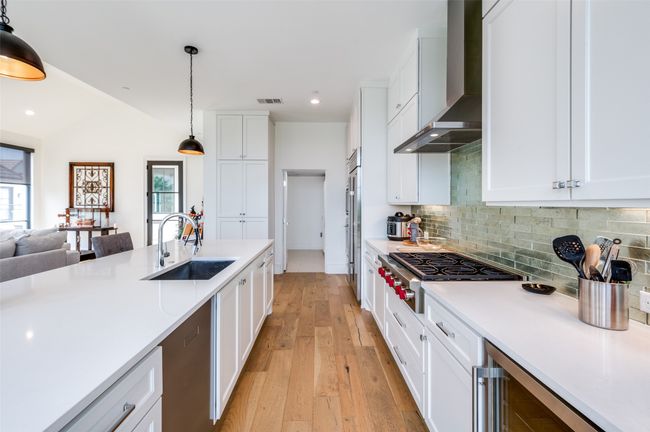 Gorgeous contemporary chef kitchen with Texas sized island perfect for entertaining equipped with stainless steel appliances, white cabinets, built in fridge | Image 10