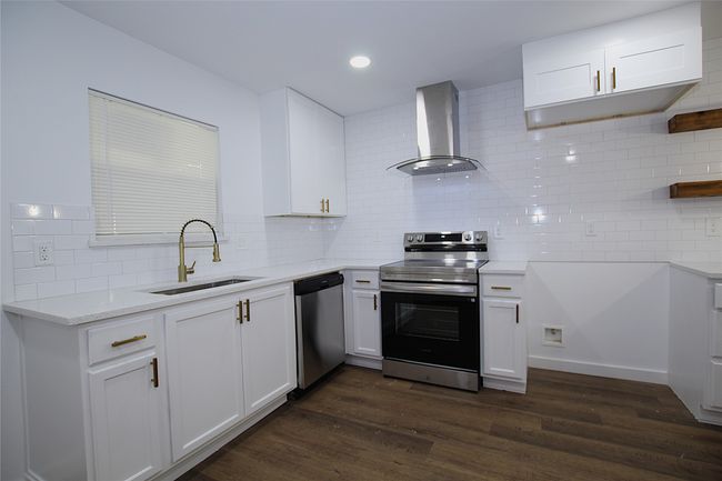 Kitchen with wall chimney exhaust hood, appliances with stainless steel finishes, decorative backsplash, and a sink | Image 6