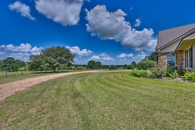Expansive lawn with a scenic rural backdrop with driveway leading around to 3 car garage. | Image 34