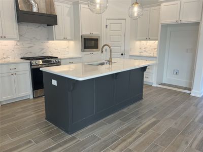 Kitchen with light hardwood / wood-style flooring, appliances with stainless steel finishes, sink, and an island with sink | Image 2