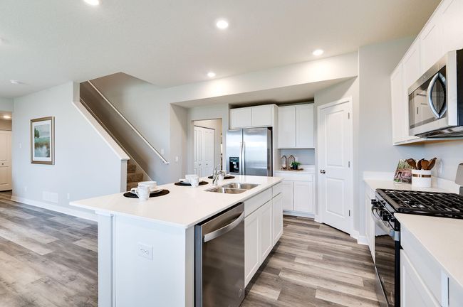 Thoughtfully-designed, modern & fresh describes this kitchen. Equipped with stainless steel appliances, quartz countertops & a large island, this kitchen adds distinction & character to the home. Photo of model home, color & options may vary. | Image 6