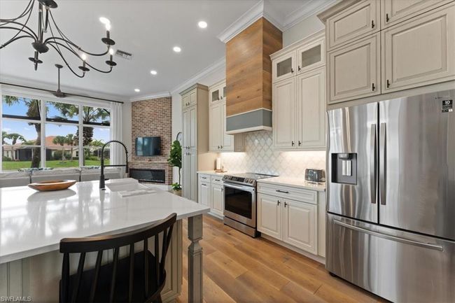Kitchen featuring appliances with stainless steel finishes, ornamental molding, light countertops, a chandelier, and a sink | Image 6