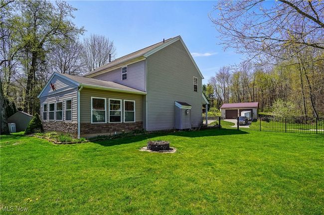 Rear view of house featuring fence, a fire pit, a yard, and an outdoor structure | Image 47