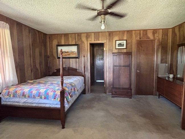Carpeted bedroom featuring a textured ceiling, wooden walls, and ceiling fan | Image 21