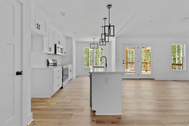 Kitchen with stainless steel appliances, light countertops, light wood-type flooring, and plenty of natural light | Image 12