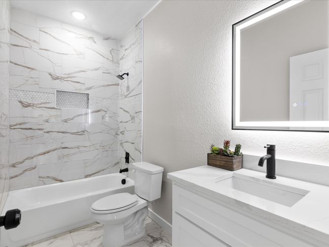 Full bath featuring vanity, shower / washtub combination, toilet, a textured wall, and marble finish floor | Image 17