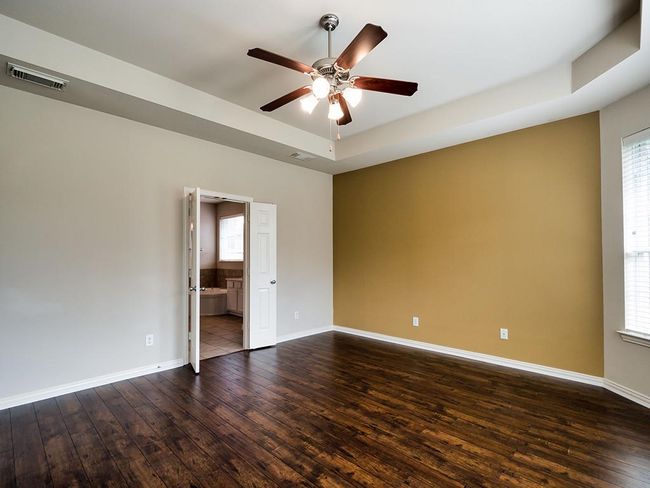 Unfurnished room featuring dark wood-type flooring, ceiling fan, a raised ceiling, and baseboards | Image 28