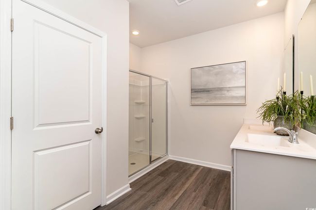 Full bath featuring a shower stall, wood finished floors, double vanity, a sink, and baseboards | Image 16