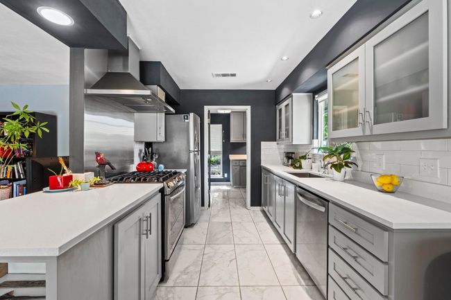 Featuring sleek updated SS appliances including a gas range with a chef's vent hood and a dishwasher. There is also a Kohler sink & faucet along with updated light fixtures, and an updated door to the Butler's Pantry. | Image 4