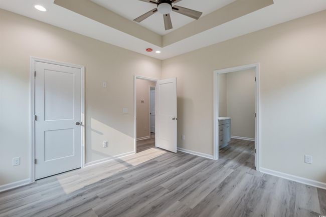 Unfurnished bedroom with light wood-style flooring, recessed lighting, baseboards, a raised ceiling, and ensuite bathroom | Image 18