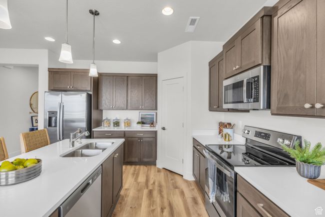 Kitchen featuring sink, hanging light fixtures, light hardwood / wood-style flooring, a kitchen bar, and stainless steel appliances | Image 13