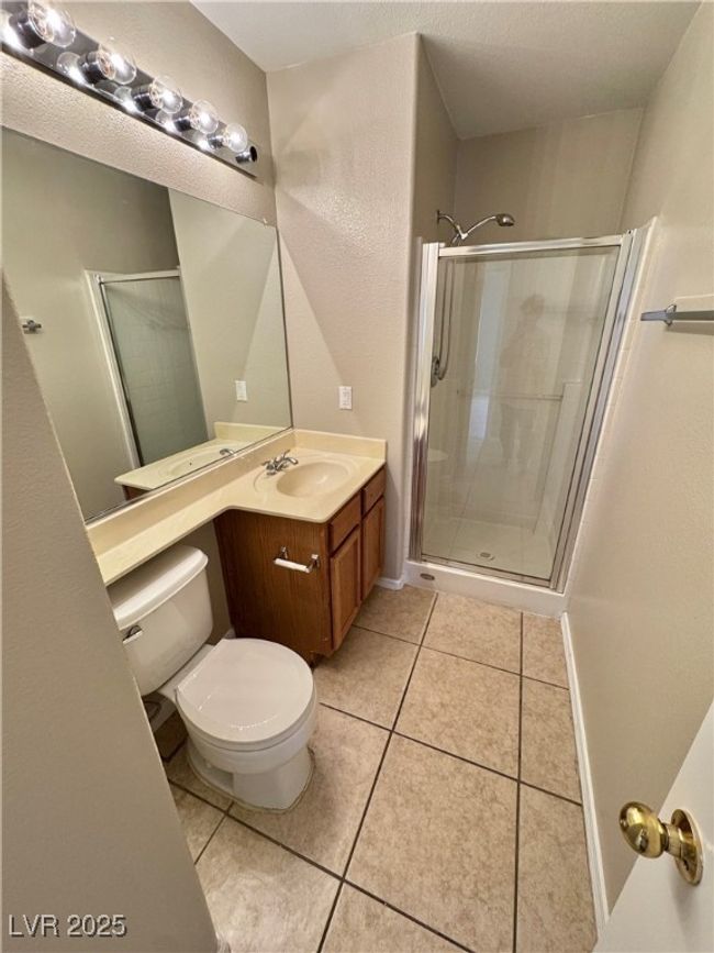 Full bathroom featuring a shower stall, toilet, vanity, and tile patterned flooring | Image 12