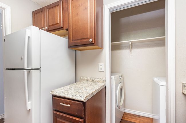 Laundry area featuring wood finished floors and washing machine and clothes dryer | Image 8