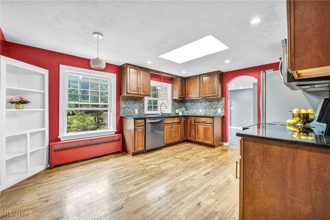 Kitchen featuring appliances with stainless steel finishes, a skylight, radiator heating unit, light wood flooring, and maple cabinetry | Image 6