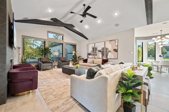 Spacious, modern living room with high ceilings, exposed beams, and large windows offering natural light and scenic views. | Image 25