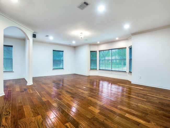 Spare room with visible vents, crown molding, baseboards, hardwood / wood-style flooring, and arched walkways | Image 5