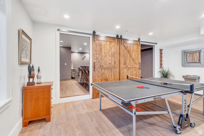 Recreation room featuring light wood-style floors, a barn door, and recessed lighting | Image 61