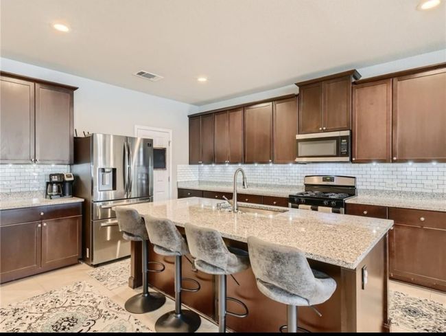 Kitchen featuring stainless steel appliances, tasteful backsplash, light stone countertops, a center island with sink, and recessed lighting | Image 13