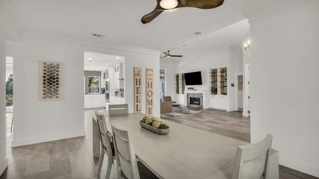Dining room with a fireplace, wood finished floors, crown molding, recessed lighting, and a ceiling fan | Image 9