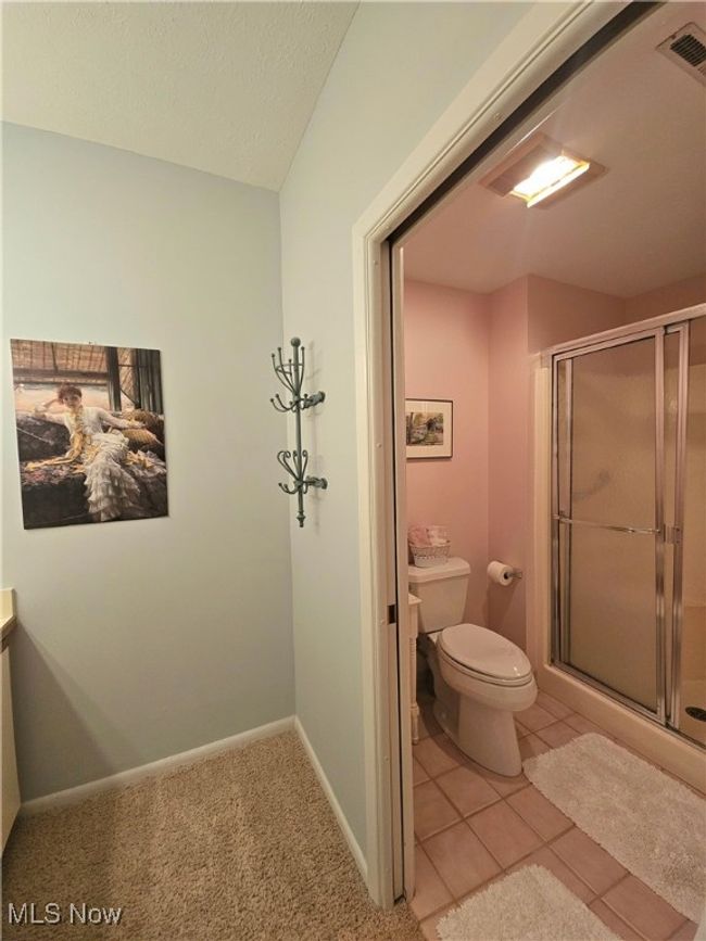Bathroom with tile patterned floors, a textured ceiling, toilet, and a shower with shower door | Image 14