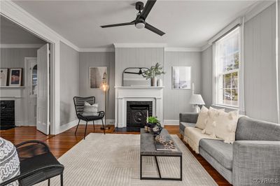 Living room with dark wood-type flooring, ceiling fan, crown molding, and beverage cooler | Image 1